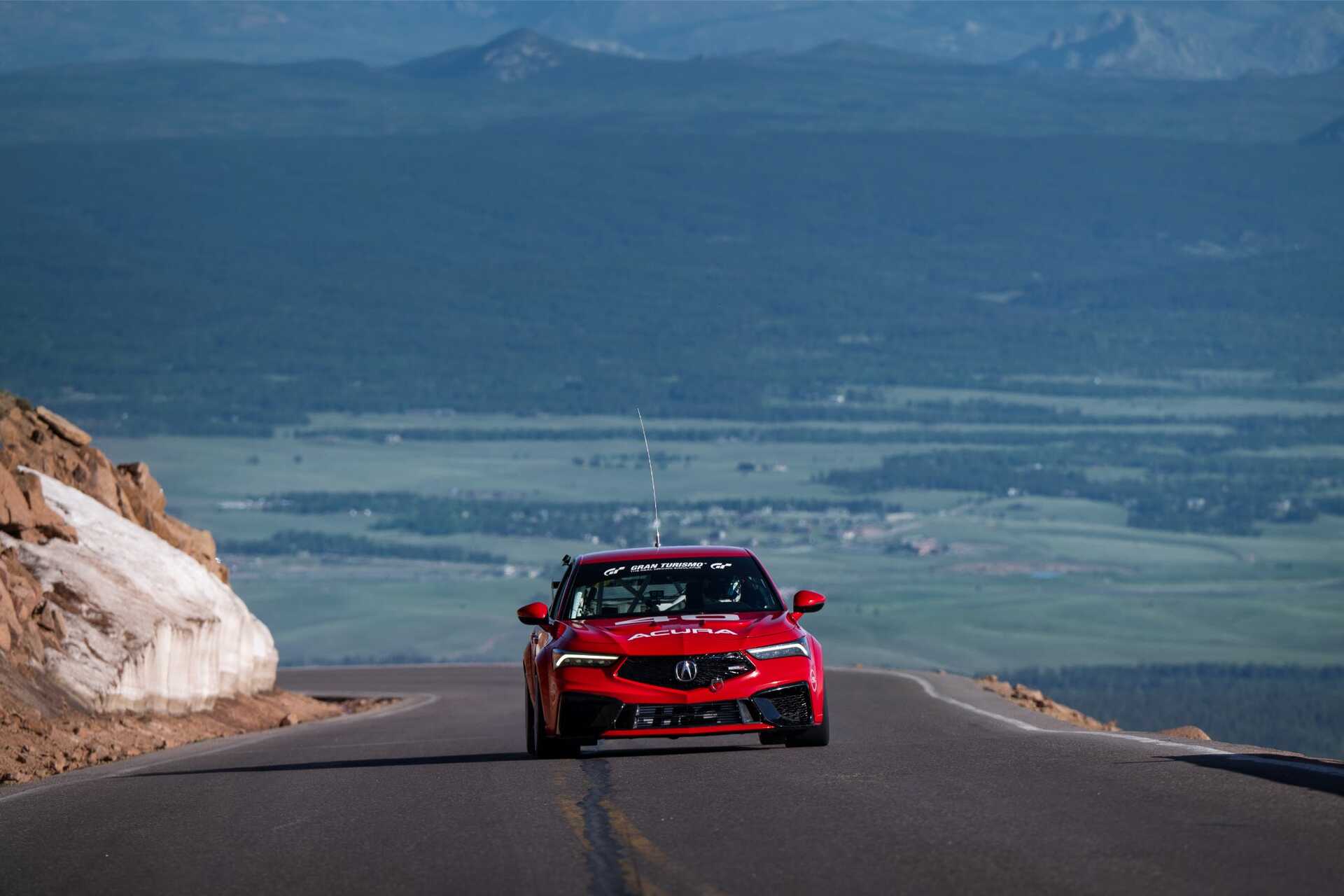 red sports car driving on a winding mountain road with a scenic background