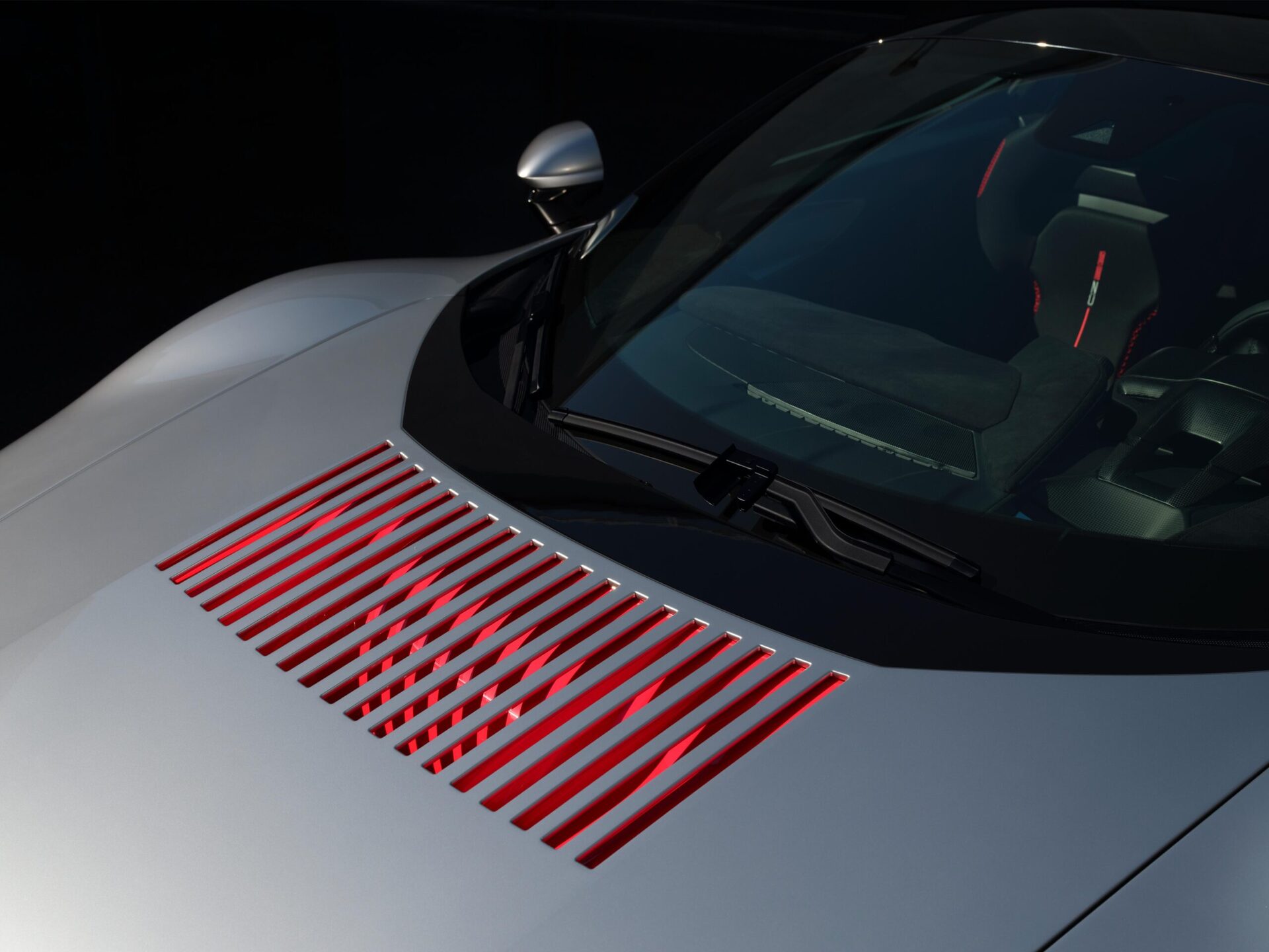 A sleek silver sports car hood with red vent slats, showcasing a modern design and luxurious detailing.