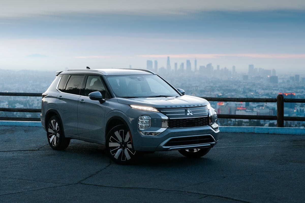 Silver Mitsubishi Outlander parked with a city skyline in the background at dusk.