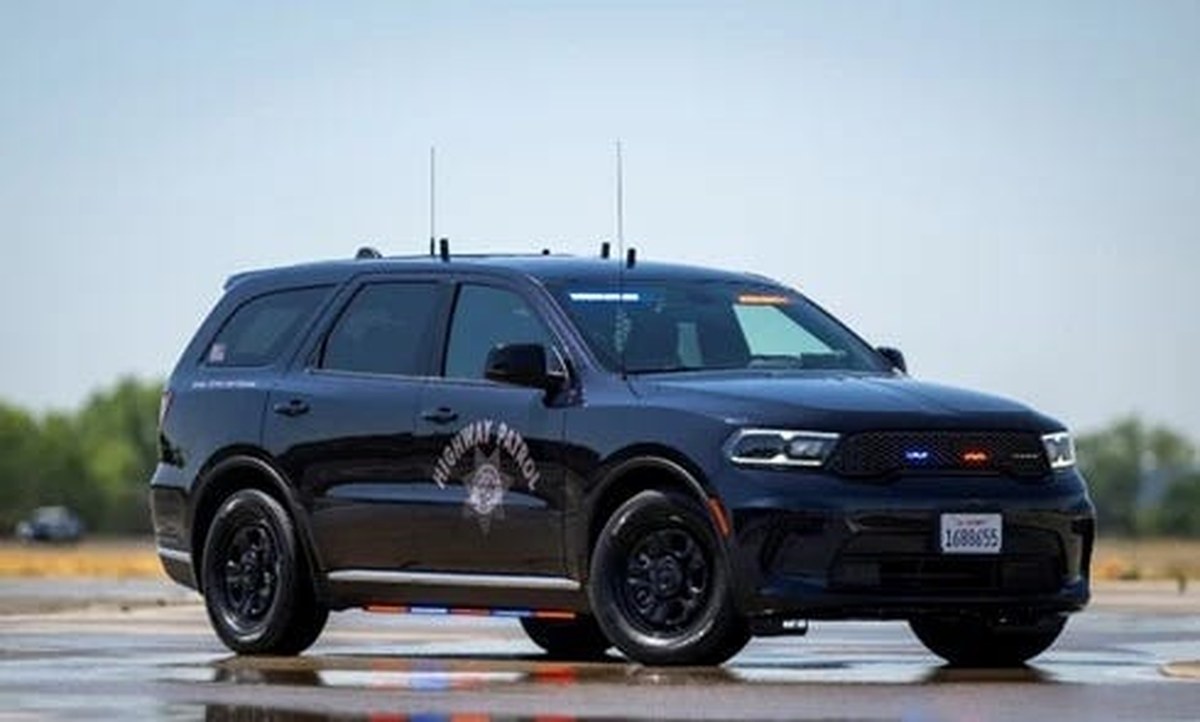dark colored police suv on a road, lights activated.
