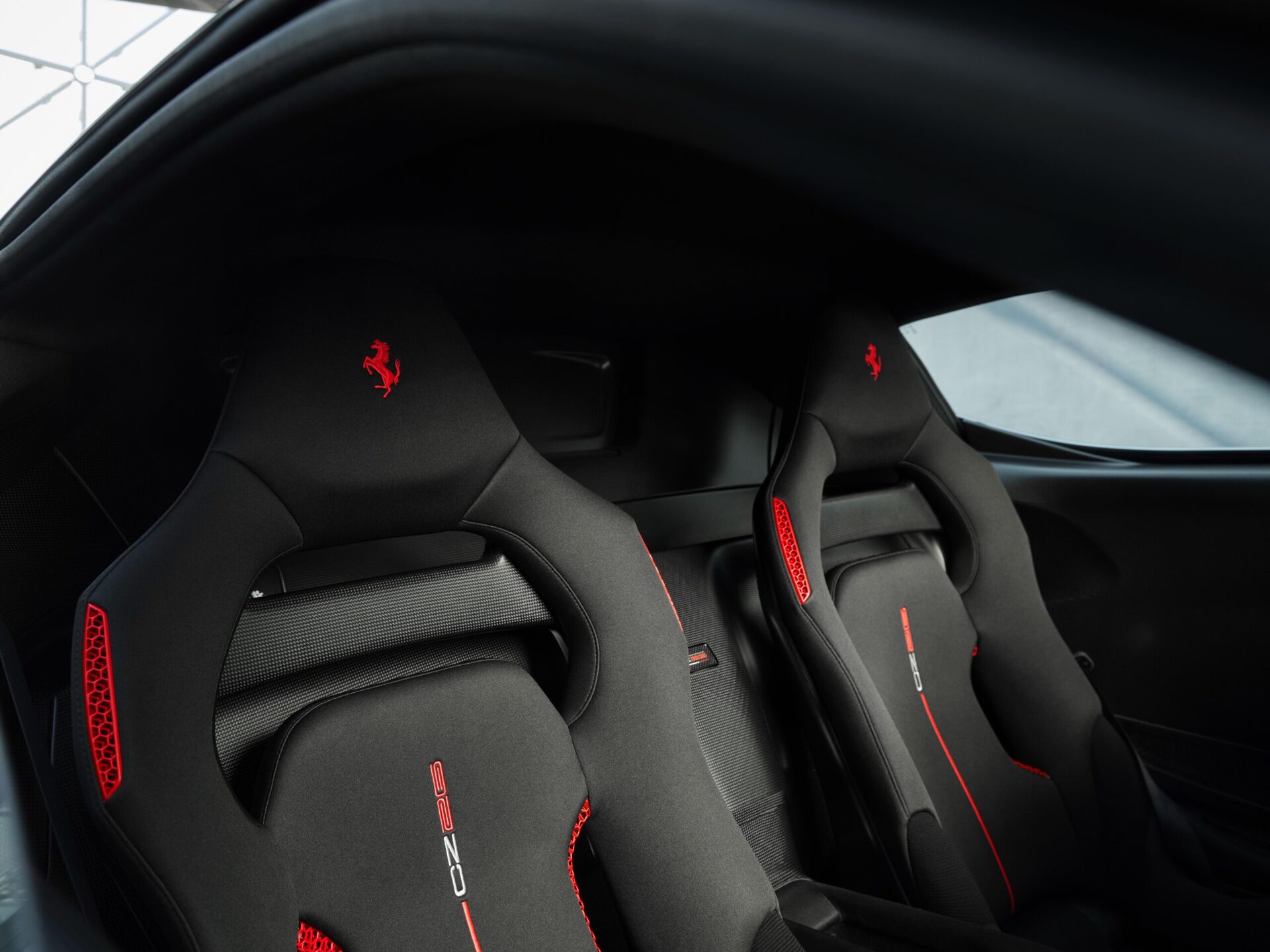 Interior view of luxurious racing seats featuring black fabric and red accents in a sleek sports car.