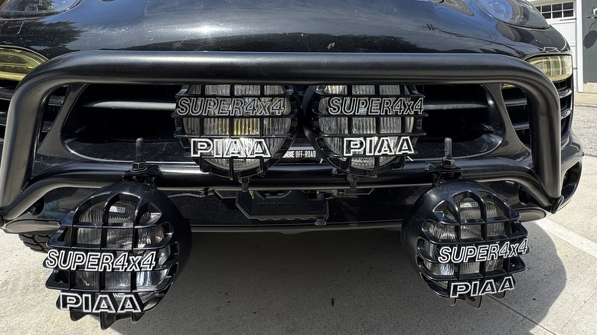 Four off-road lights mounted to the front bumper of a Porsche Cayenne