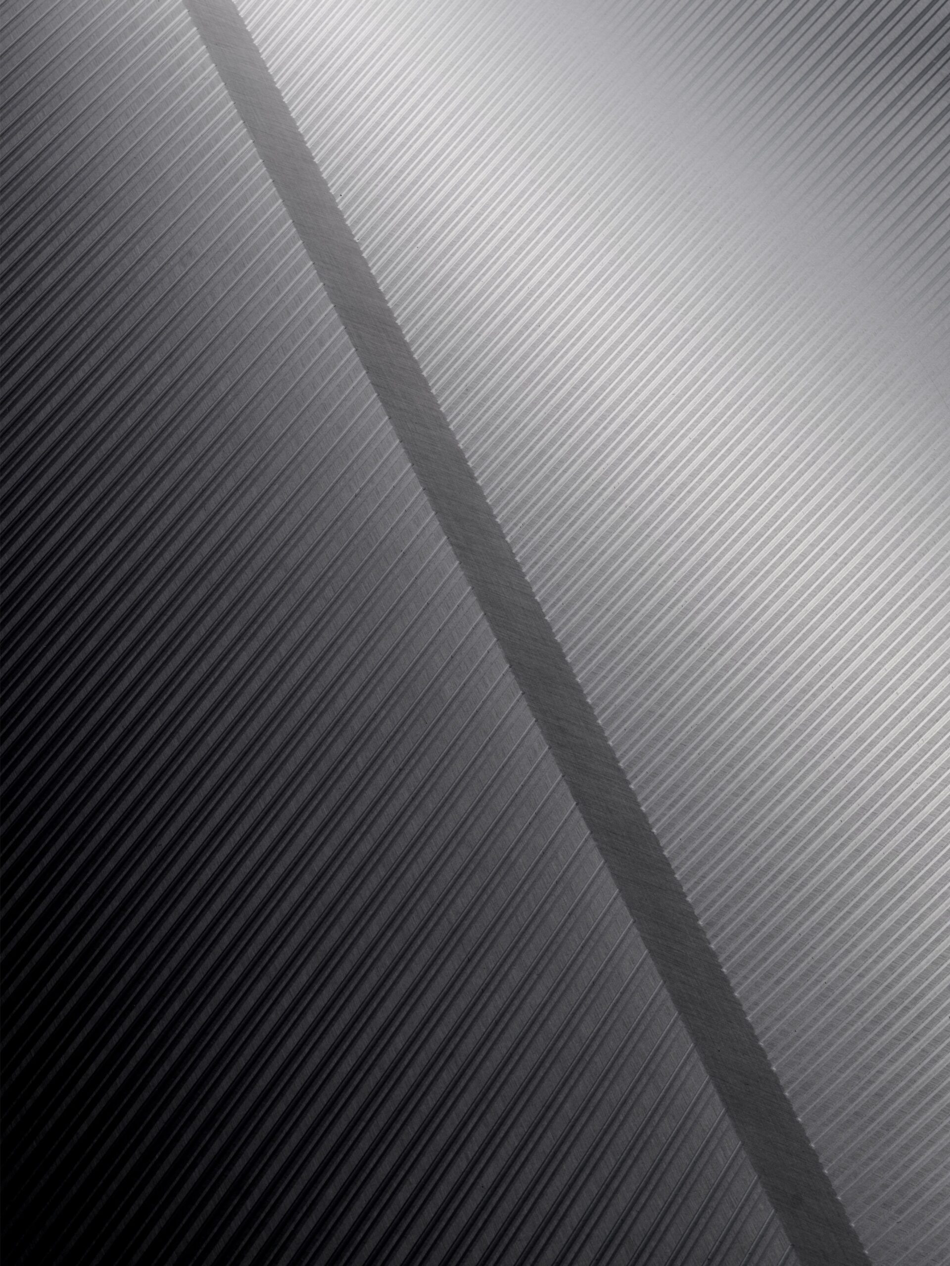 Textured metallic surface with contrasting diagonal stripes in shades of gray.