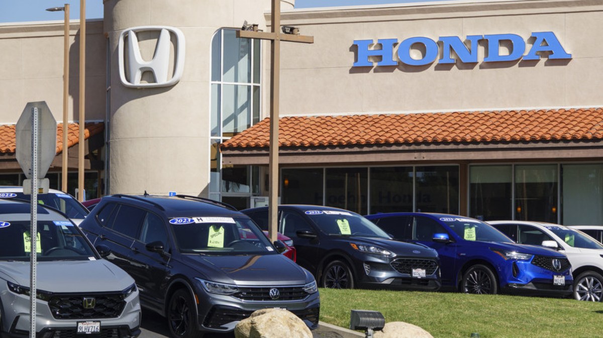 a honda car dealership in california. used vehicles from multiple automakers sit on the front lawn with green pricing tickets hanging from their rearview mirrors
