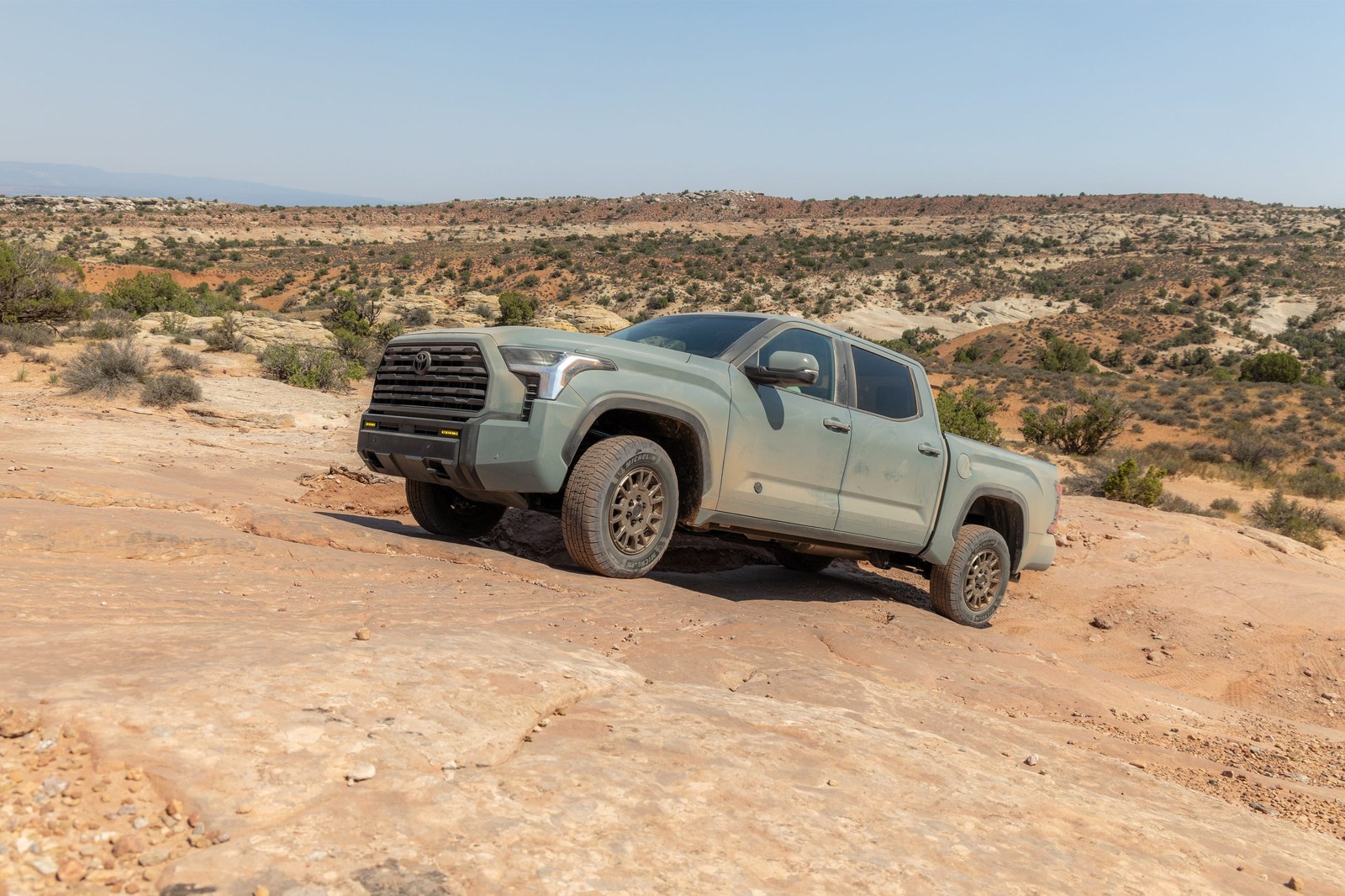 A rugged pickup truck navigating rocky terrain against a scenic desert landscape. A rugged pickup truck navigating rocky terrain against a scenic desert landscape.