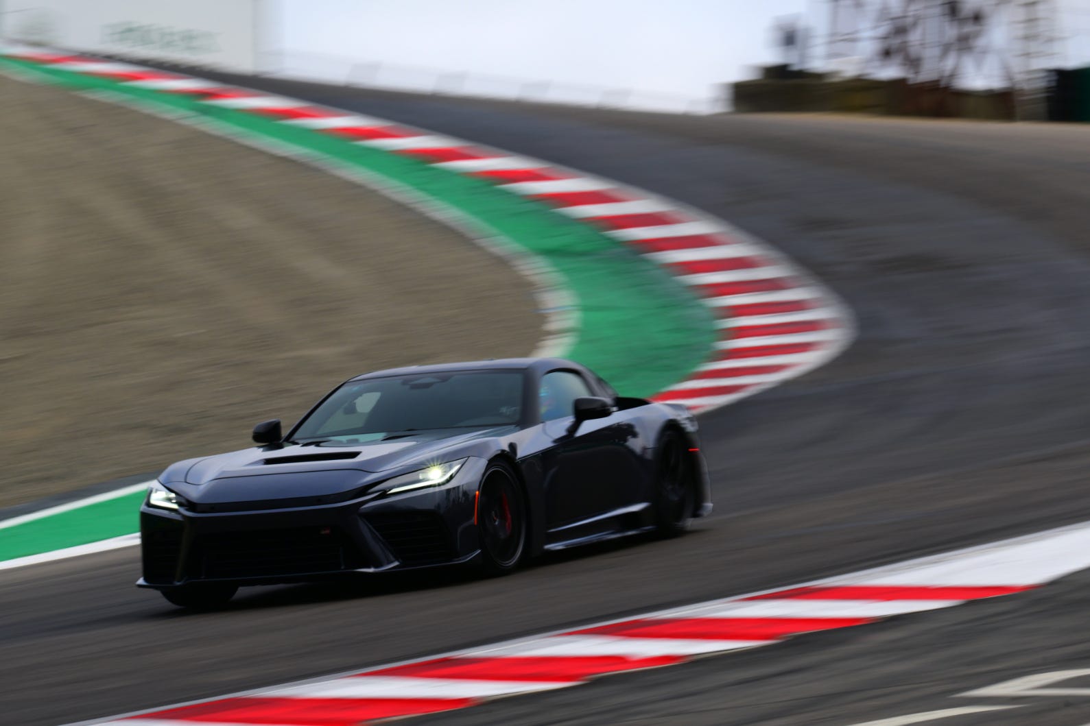 A sleek black sports car navigating a winding racetrack with vibrant corner markings. A sleek black sports car navigating a winding racetrack with vibrant corner markings.
