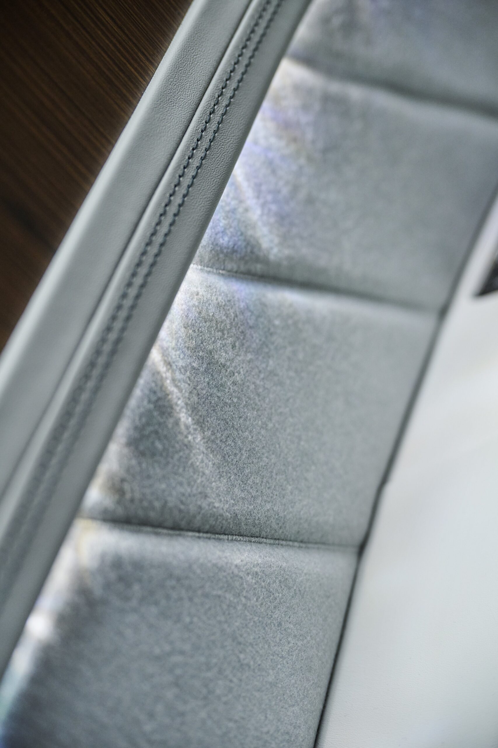Close-up of textured fabric and stitching on a sleek, modern surface.