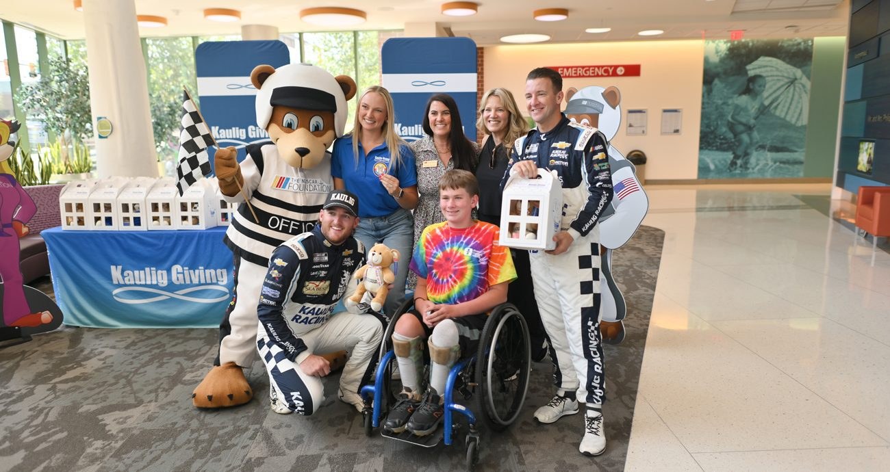 Group shot of The NASCAR Foundation, Kaulig Racing, Kaulig Giving and a hospital patient with a Speedy Bear.