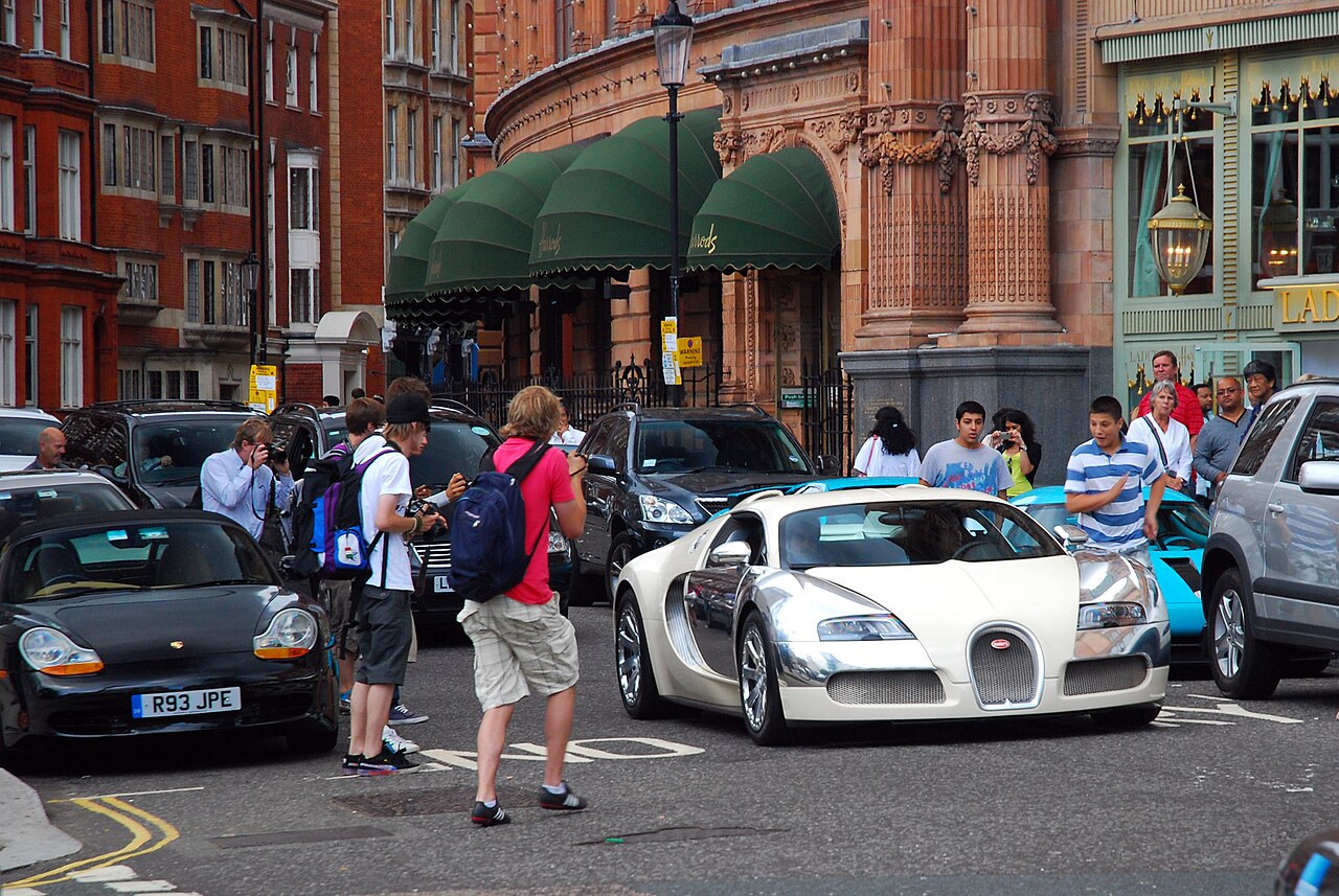 Car spotters observing and photographing a Bugatti Veyron outside Harrods in Knightsbridge, London, England