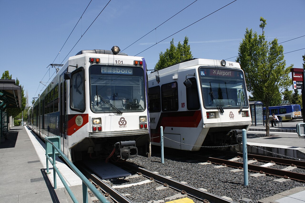 Two types of light rail car on the MAX system in Portland, Oregon, both fitted with rollsigns, in 2009. This photo illustrates how rolls/blinds allow use of color and of symbols, such as the airplane icon shown here.