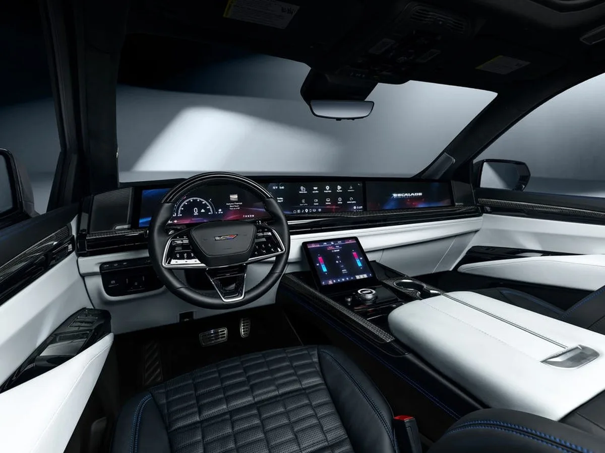 vehicle interior view, black and white cabin with wide digital display, steering wheel and center touchscreen.