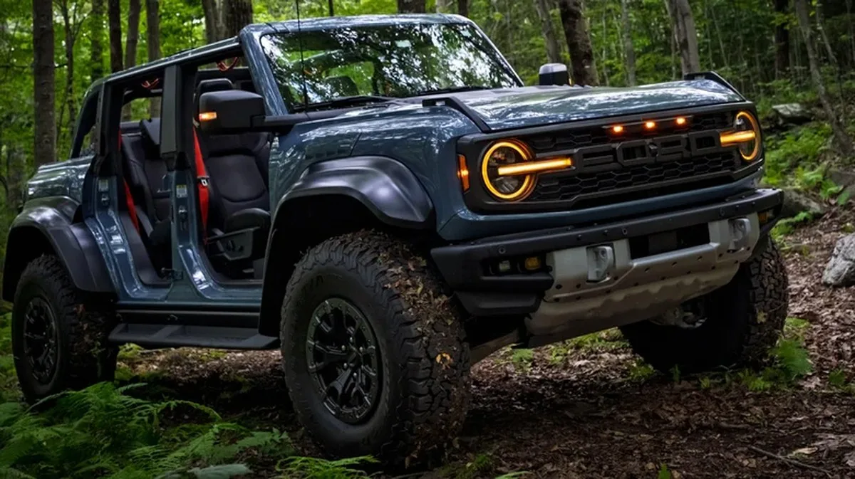 Blue Ford Bronco Raptor with doors and roof off in the woods