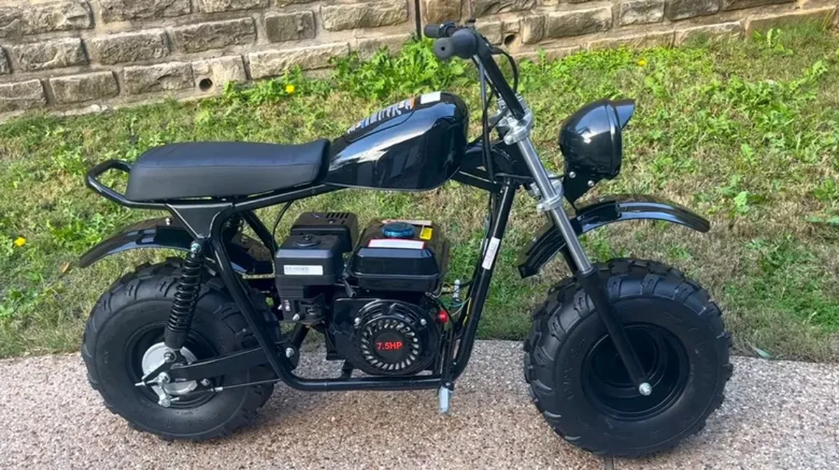A black Massimo MB 200S mini bike parked on a driveway next to a lawn