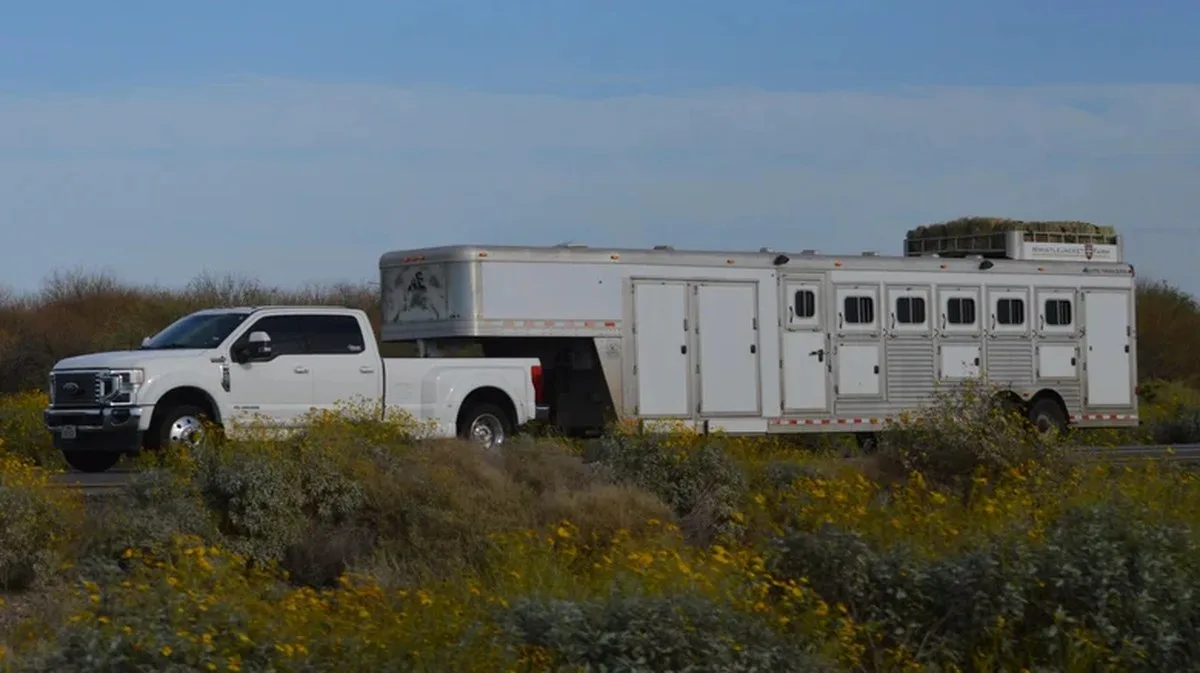 A white Ford F-450 towing a massive trailer with a Gooseneck hitch.
