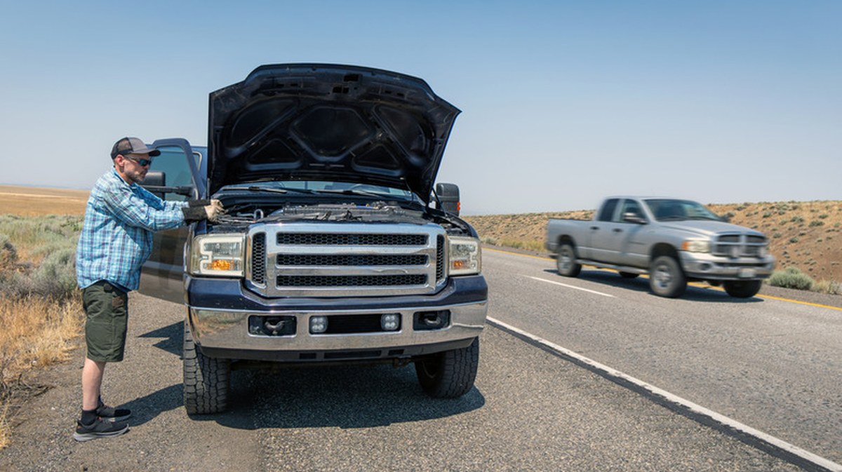 A truck with its hood up on the side of the road