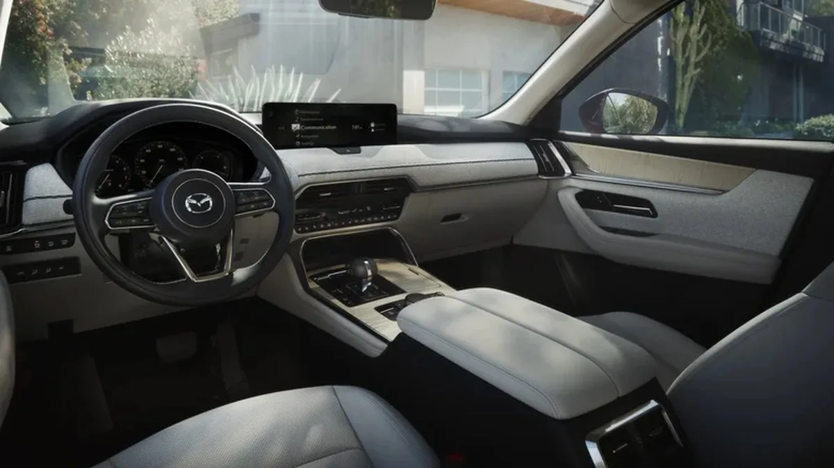The white dashboard in a CX-90 with plants and a building visible out the windows