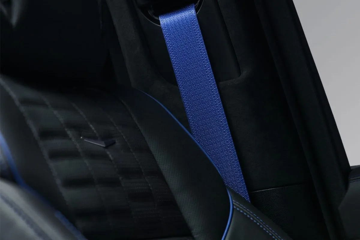 Close-up of a car seat featuring black leather with blue stitching and a blue seatbelt. Close-up of a car seat featuring black leather with blue stitching and a blue seatbelt.