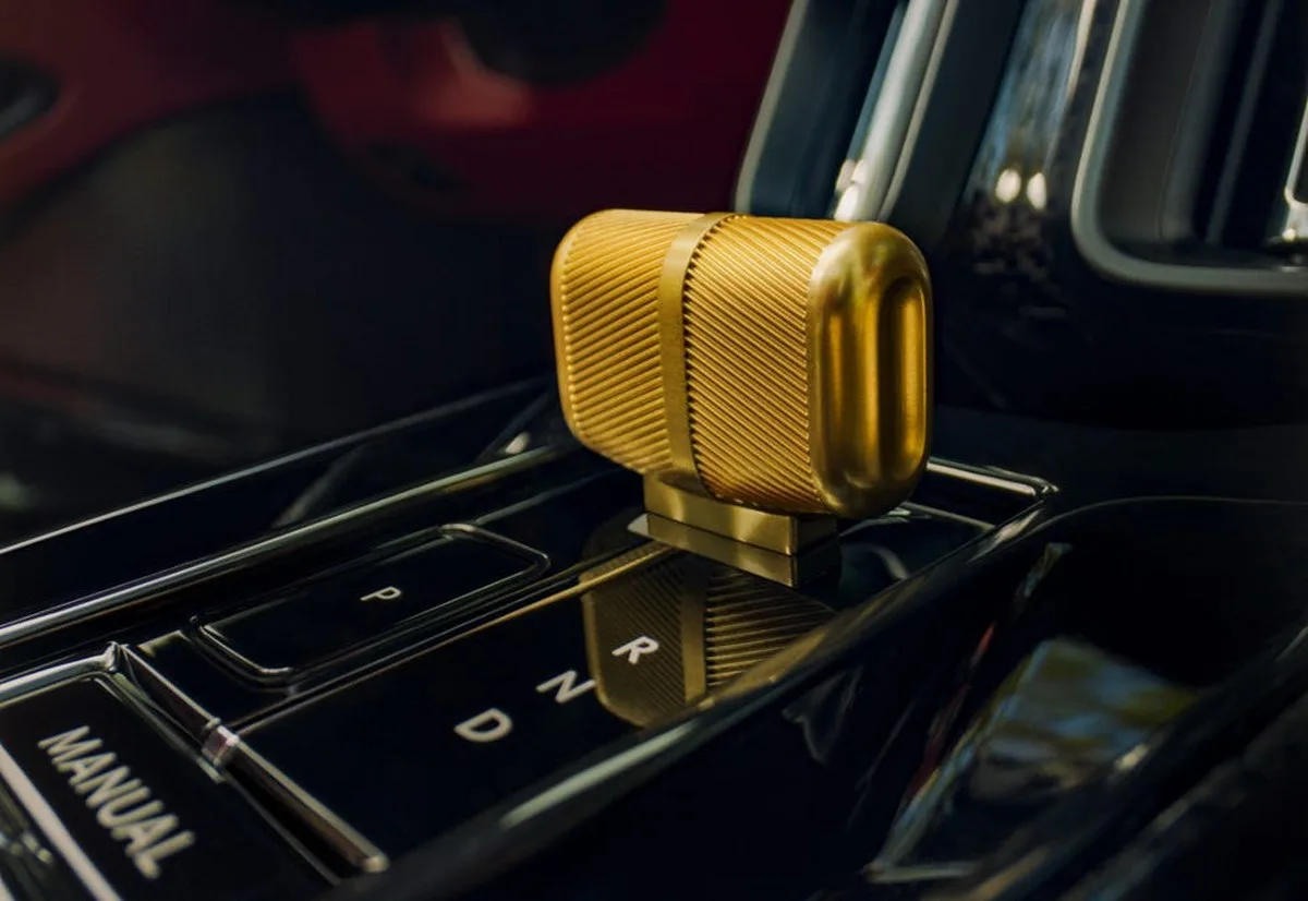 Golden gear shift knob on a car console with lettering for parking, neutral, and drive options. Golden gear shift knob on a car console with lettering for parking, neutral, and drive options.