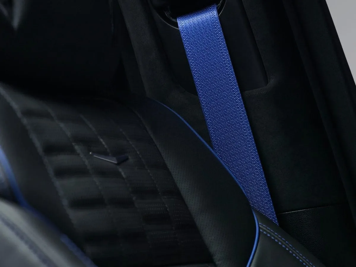Close-up of a car seat featuring a black fabric design and a blue seatbelt.