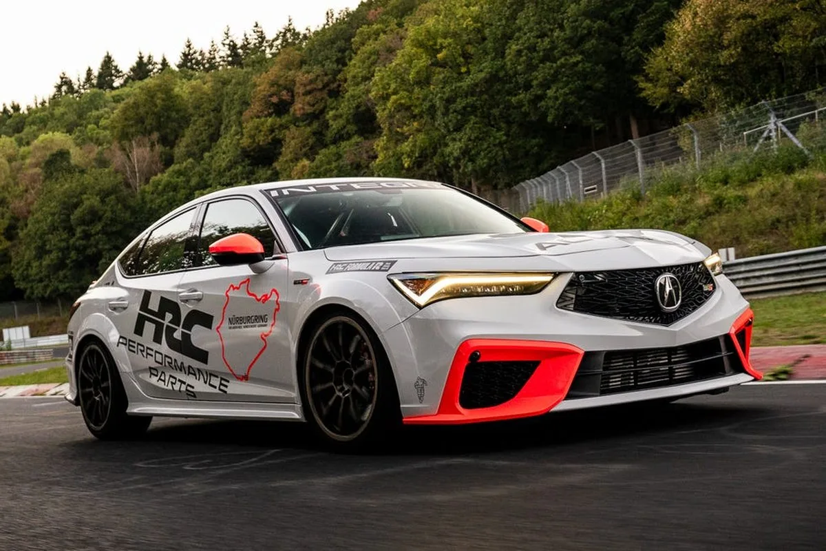 Sporty car with vibrant accents driving on a racetrack surrounded by trees.