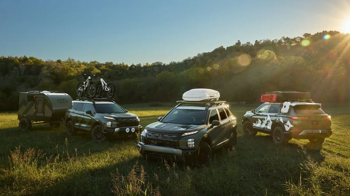 Three Mitsubishi SUVs parked in a field.